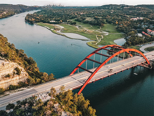 Vista aérea de un río y un puente en Austin, Texas, con la ciudad al fondo.