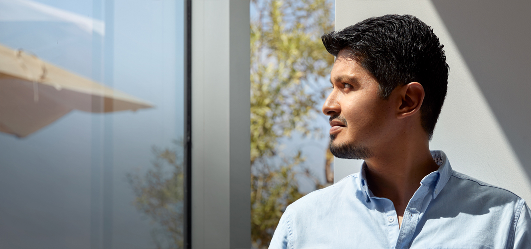 Vista de perfil de Edgar mirando por una ventana.