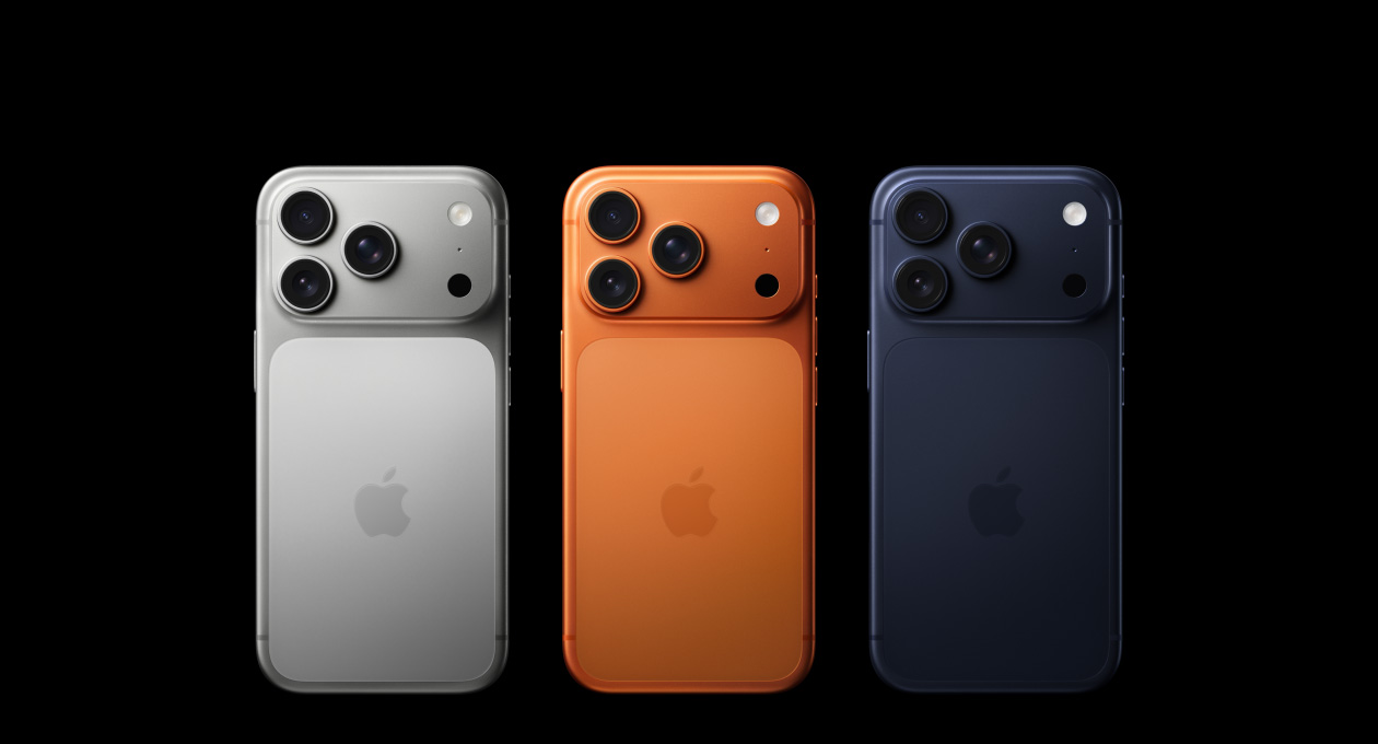Vista traseira de três modelos iPhone 17 Pro: prateado, laranja cósmico e azul escuro, com o sistema de câmaras Pro no canto superior esquerdo, 3 lentes, microfone, flash e logótipo Apple no centro