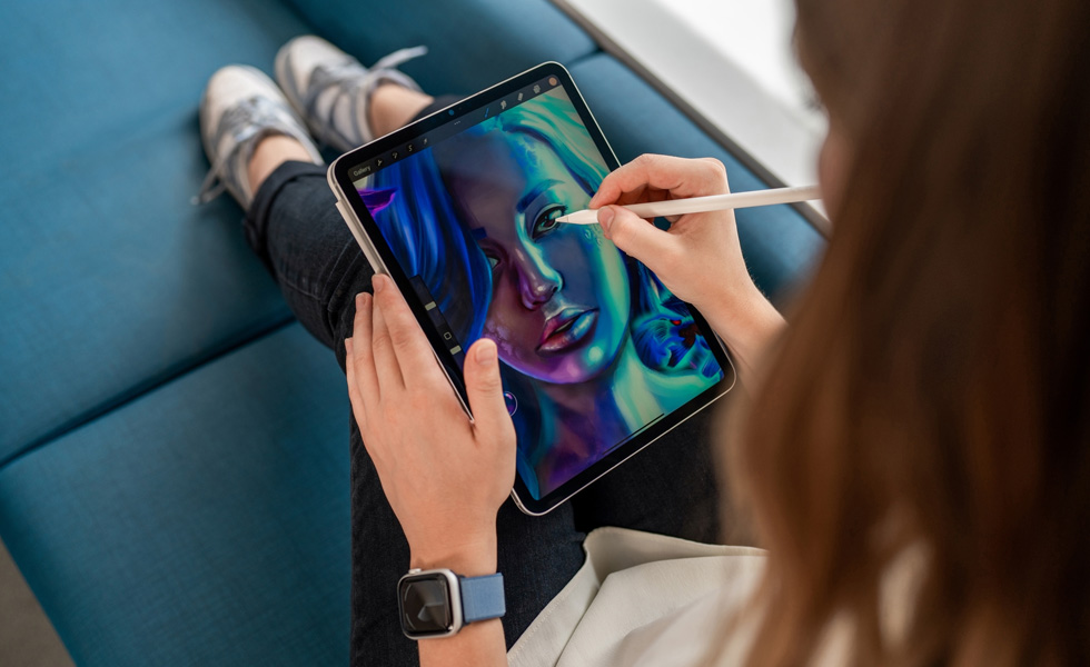 Một sinh viên đang đặt iPad trên đùi và dùng Apple Pencil để vẽ trên ứng dụng Procreate