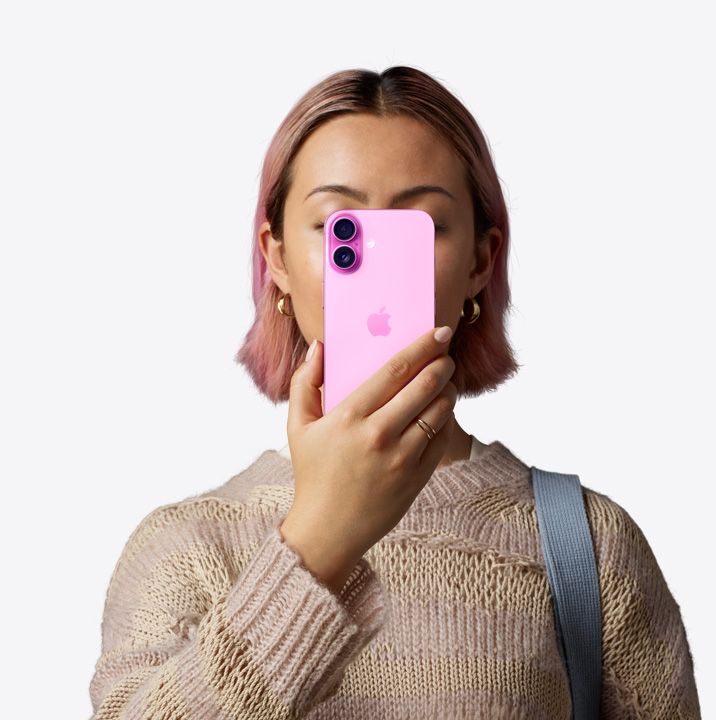 Una persona sostiene un iPhone 16 rosa frente a su cara mostrando la parte posterior y el sistema de dos cámaras en la esquina superior izquierda.