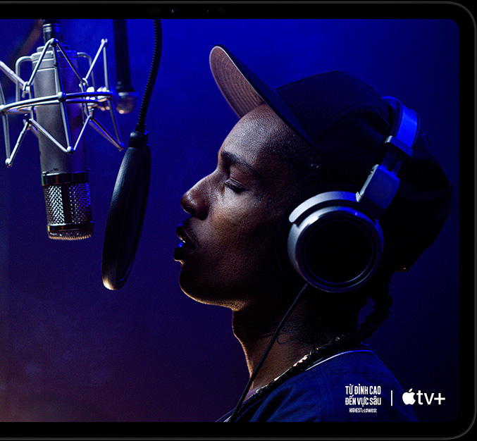 iPad Pro, nằm ngang, vỏ ngoài mặt trước, màu đen không gian, các góc được bo tròn, viền màn hình màu đen, màn hình hiển thị AppleTV+ đang phát cảnh ASAP Rocky (thủ vai Yung Felon) đọc rap trước micrô trong phim gốc của Apple TV+ mang tên 